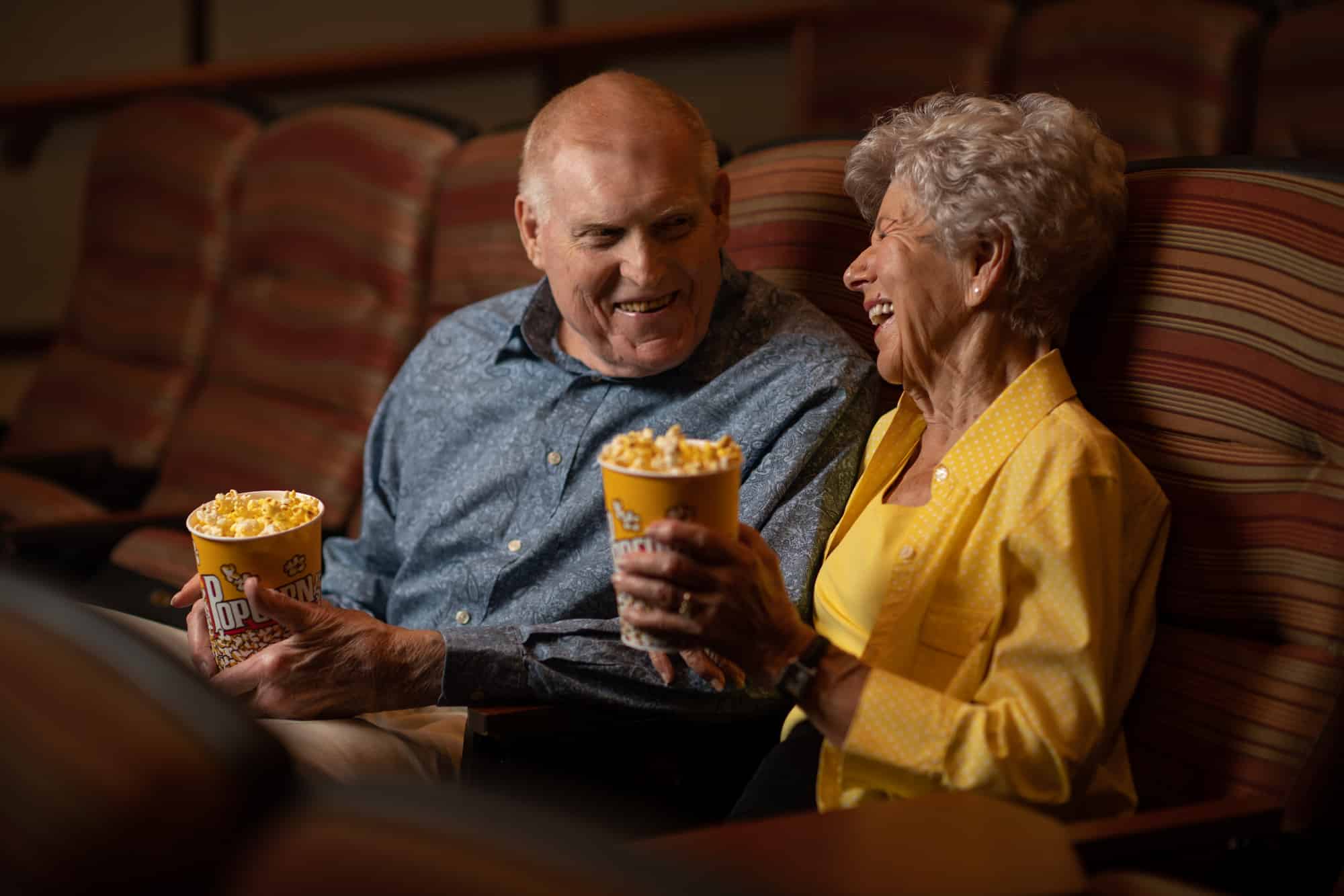 elderly couple enjoying popcorn at a movie theater