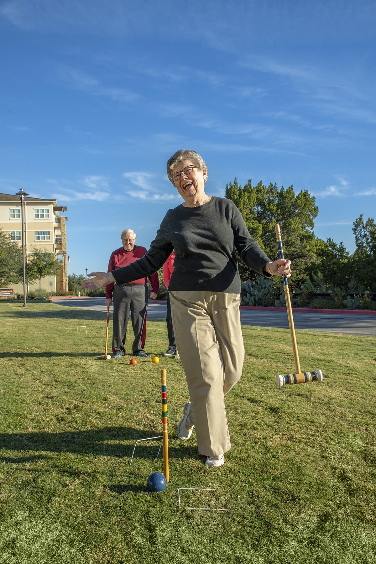 Senior woman laughing and having fun playing croquet at senior living community