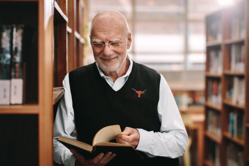 older citizen reading a book in library