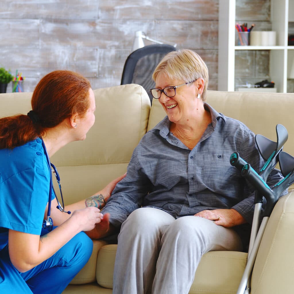Female nurse talking with old woman with alzheimer in nursing home