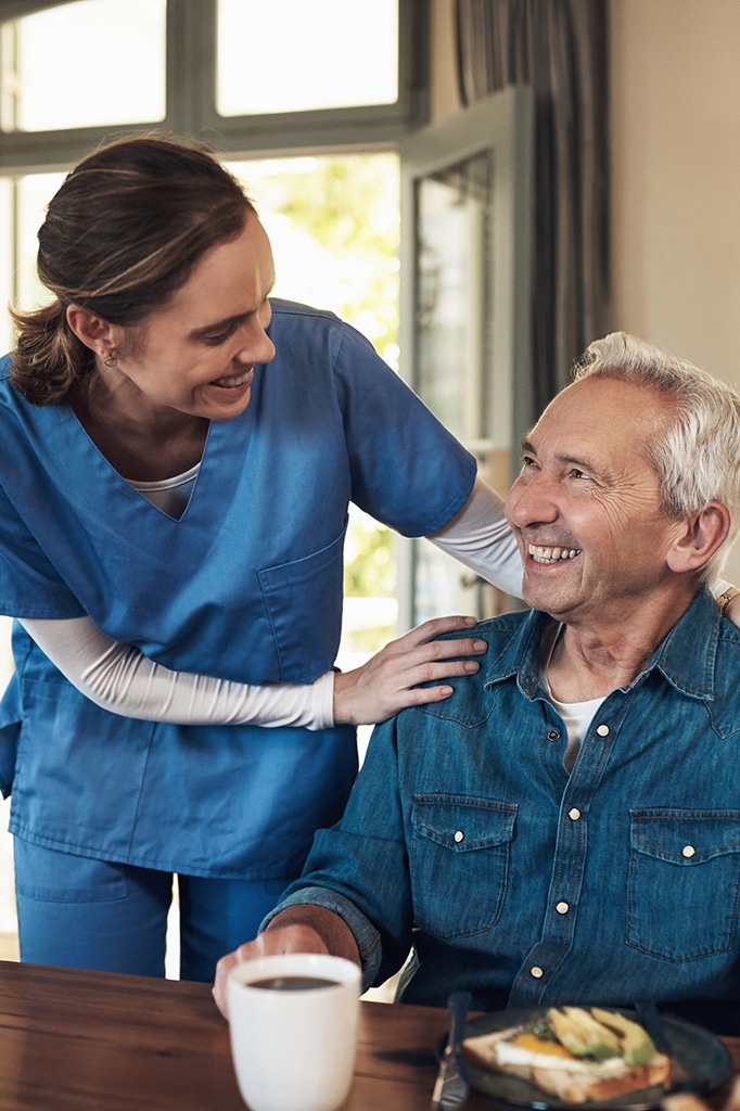Shot of a young nurse checking up on a senior man during breakfast at a nursing home.