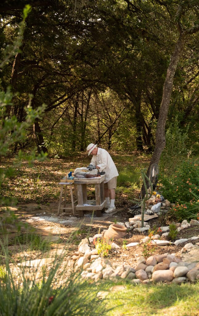 elderly man sculpting rocks in an outdoor garden
