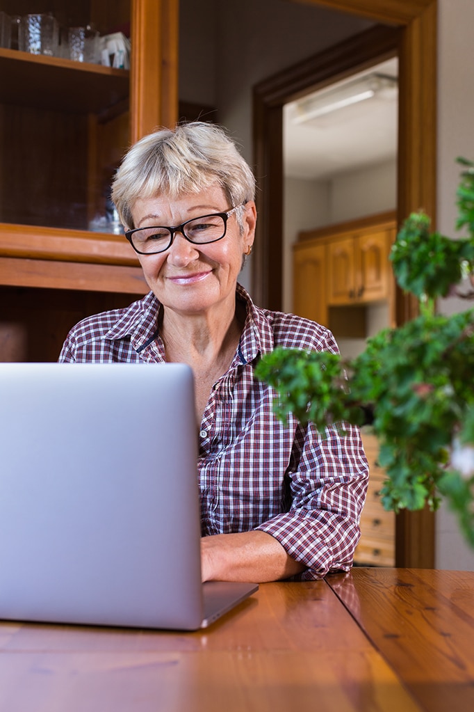 Senior woman using laptop, watching online webinar at home
