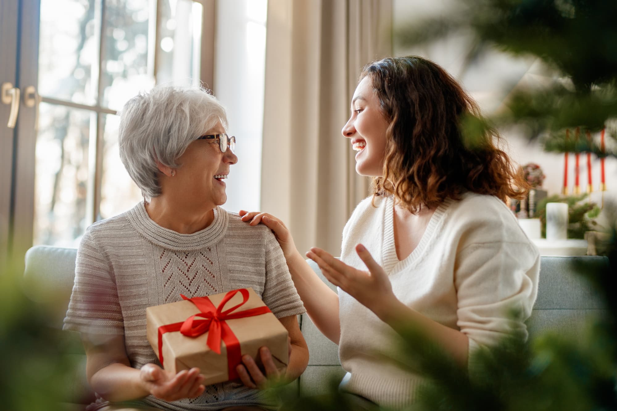 A senior woman getting a gift wrapped nicely in a box as she chats with a younger woman who smiles back at her