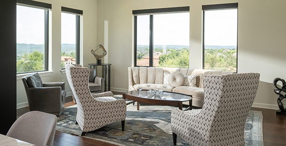 Living room in a Ballantyne apartment with seating and large windows overlooking the landscape