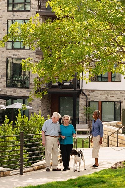 a senior couple walking securely through the outdoor campus at Longhorn Village