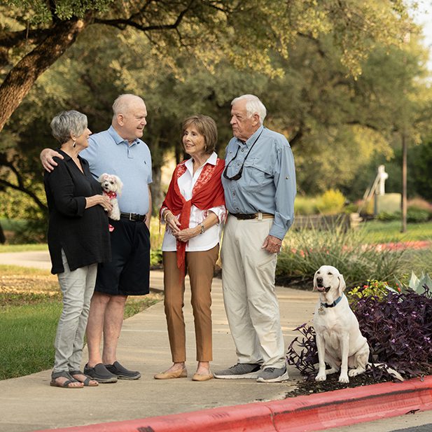 group of residents chatting outdoors in the campus, with a dog