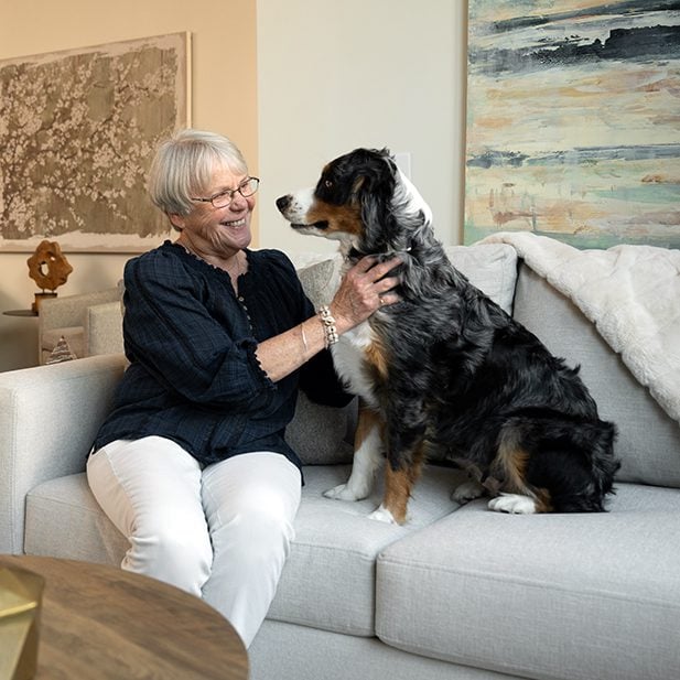 senior woman petting her dog on the couch in her senior apartment
