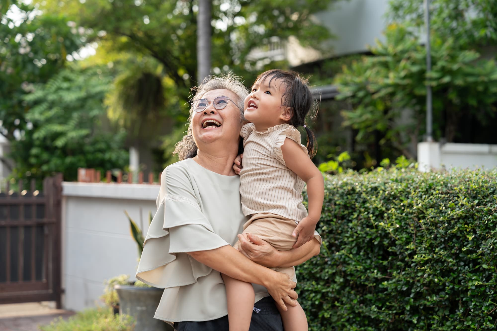A senior women grandparent holding her grandchild with a smile as they do an activity together