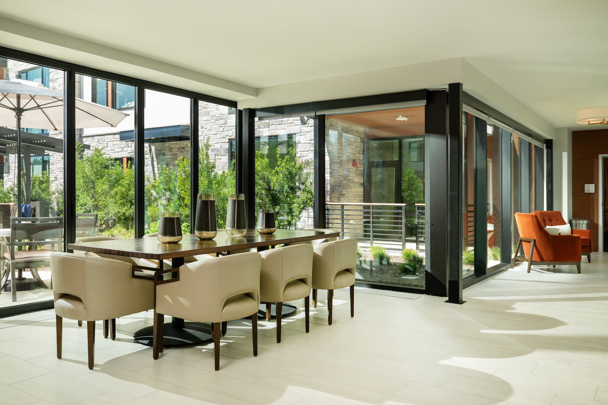 Inside Longhorn Village interior with a long table and white sofa chairs, with a view of outside with glass walls.