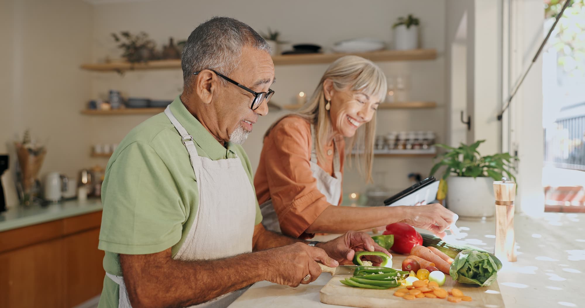 senior couple chops vegetables in the kitchen