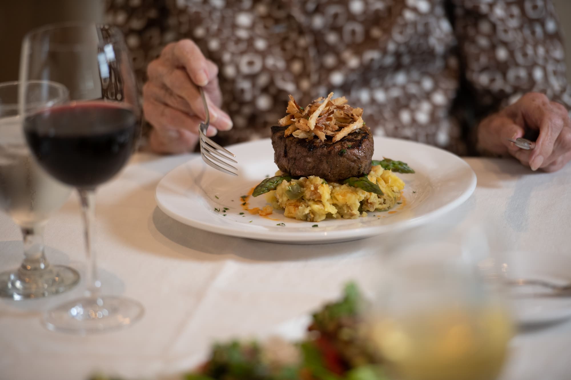 a fine dining table set with an entree of beef set upon a bed of rice.