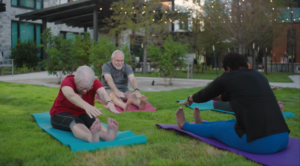 group of seniors do yoga in the outdoor lawn with an instructor