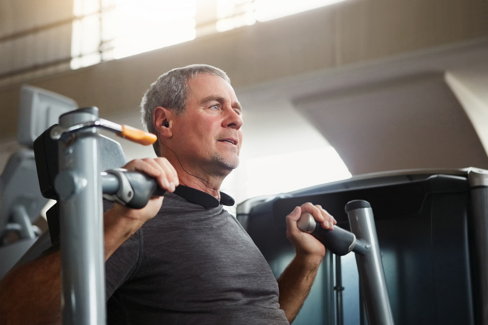 senior man does shoulder presses on a workout machine