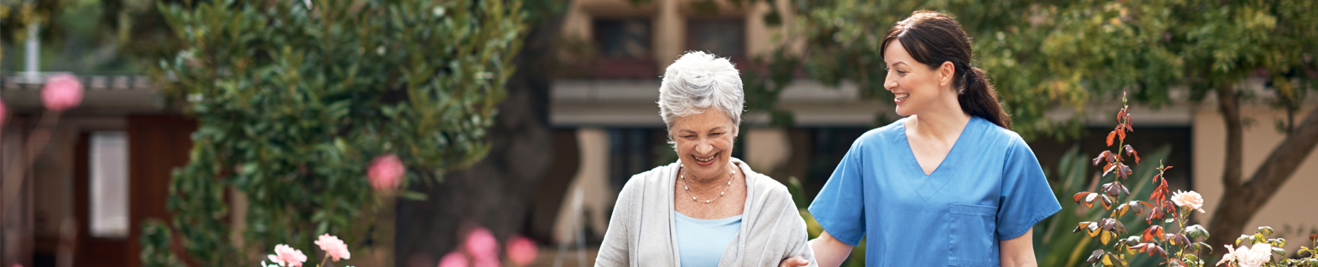 full image of senior woman walking with skilled nurse woman in garden area