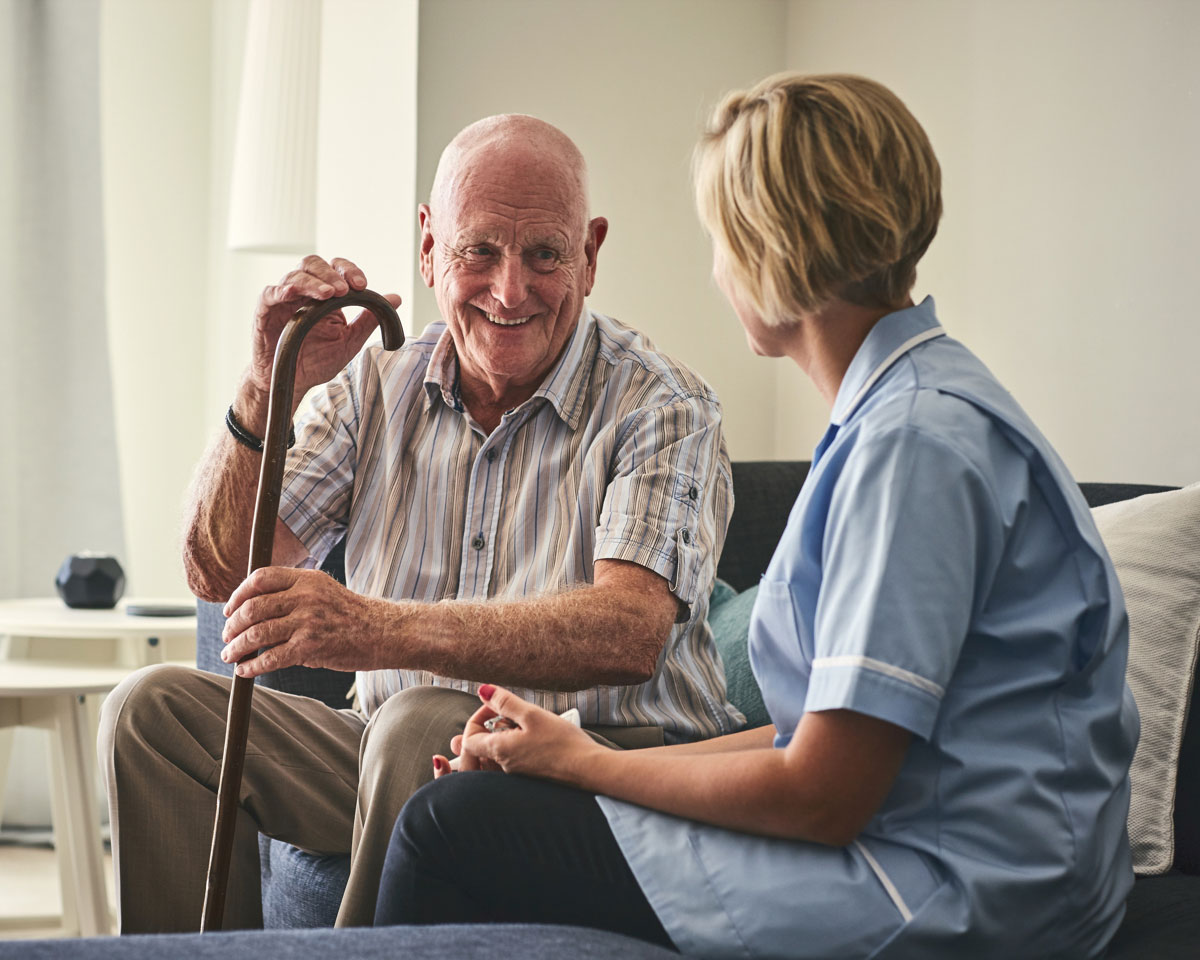 senior man with cane talking to female skilled nurse